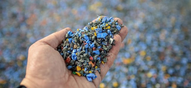 Hand holding recycled plastic chips as raw material in production